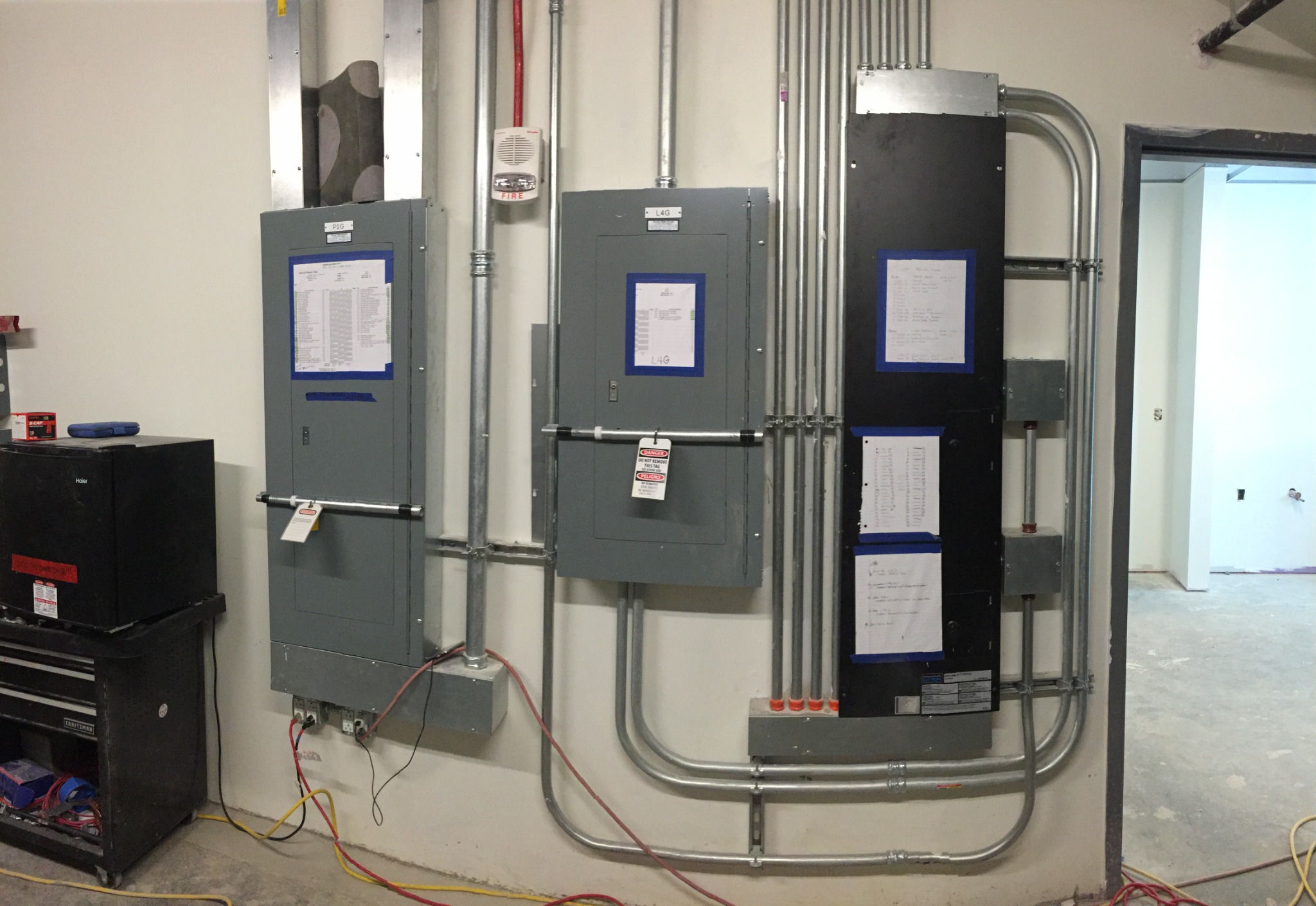 Electrical control panels and conduit in a mechanical room, showing connected equipment and work systems.